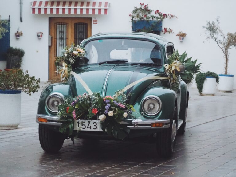 Volkswagen Escarabajo verde de 1975 decorado con flores naturales para boda en Valencia, vista frontal con detalles del capó y faros cromados